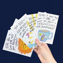 Load image into Gallery viewer, A hand holding multiple A6 postcards with colorful designs and motivational messages showcasing A6 postcard printing.